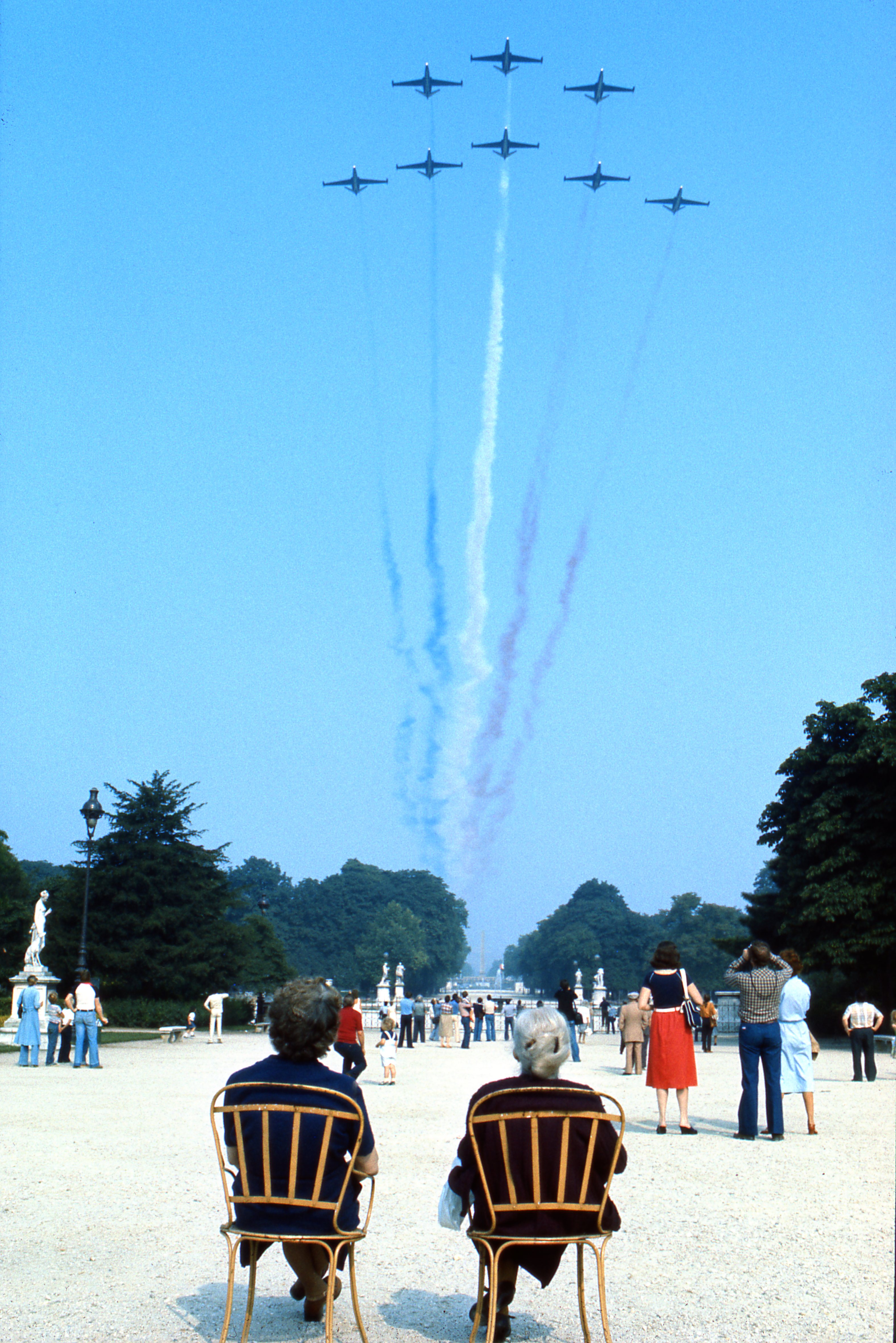 Airplanes performing a flyover in Paris, with spectators watching.