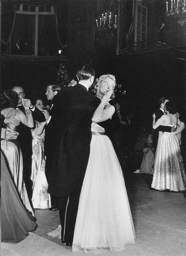 Black and white photo of a couple waltzing at a ball.