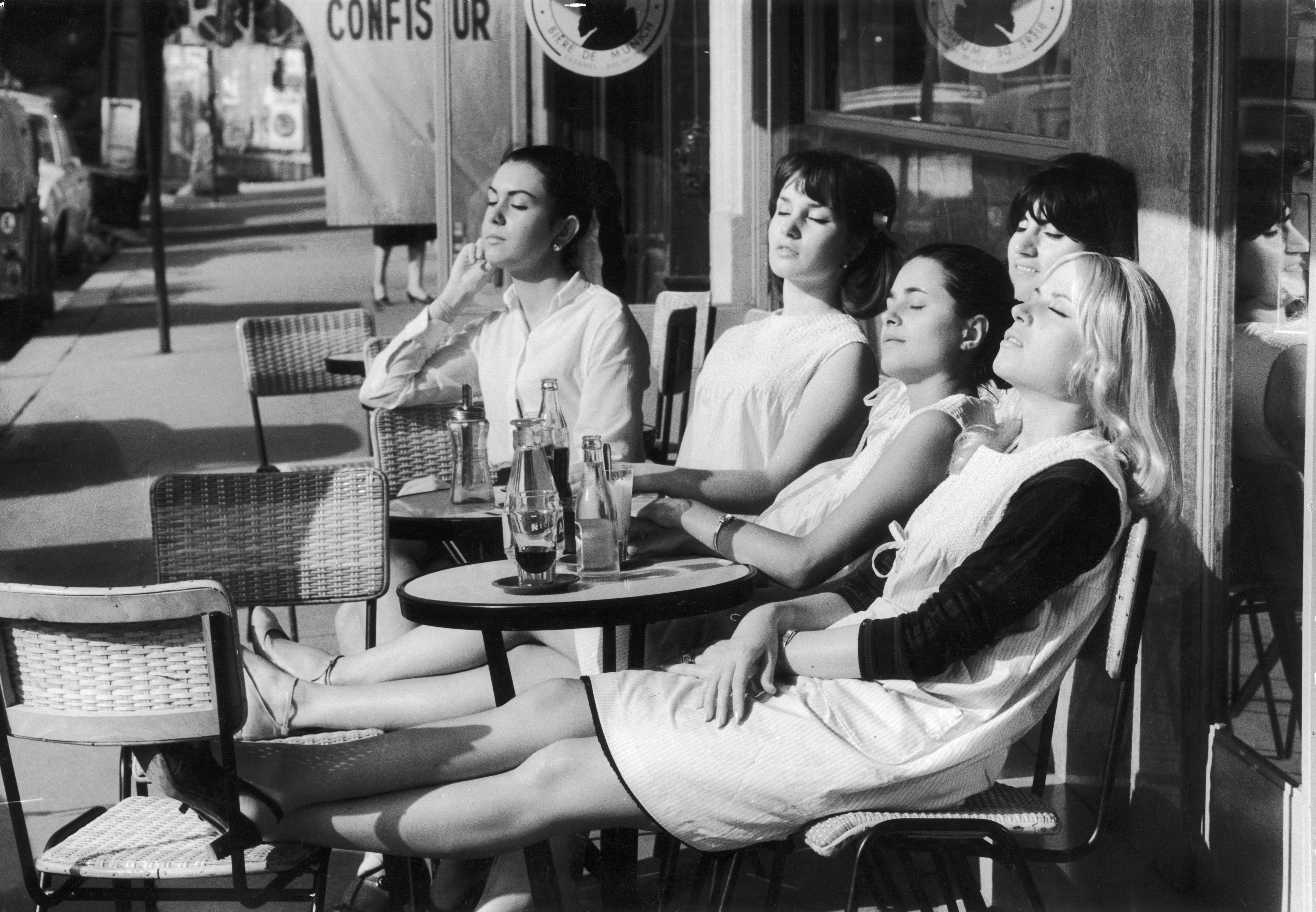 Black and white photo of four young women sitting at a Parisian cafe.