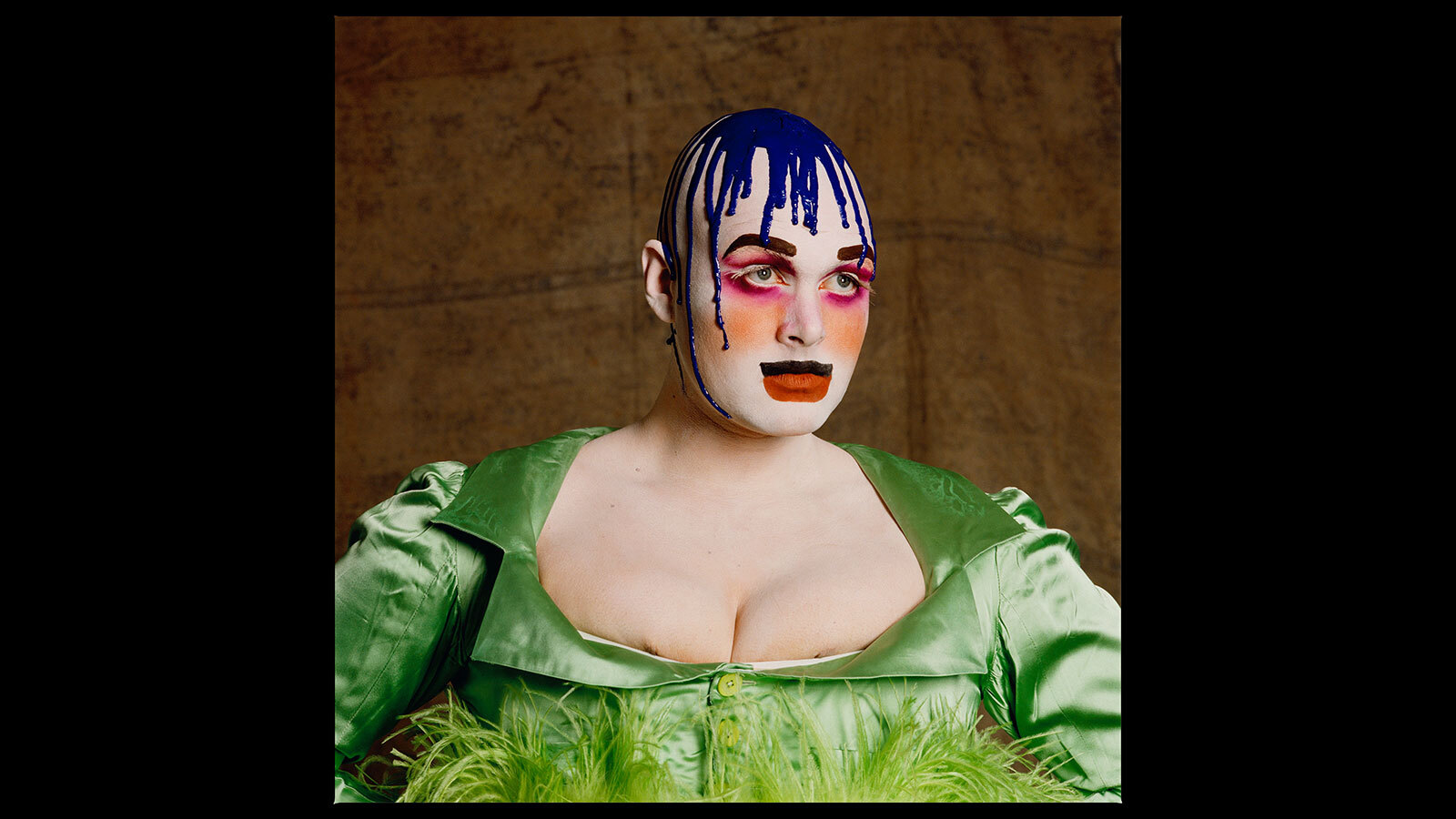 Portrait of Leigh Bowery in a green dress and elaborate makeup.