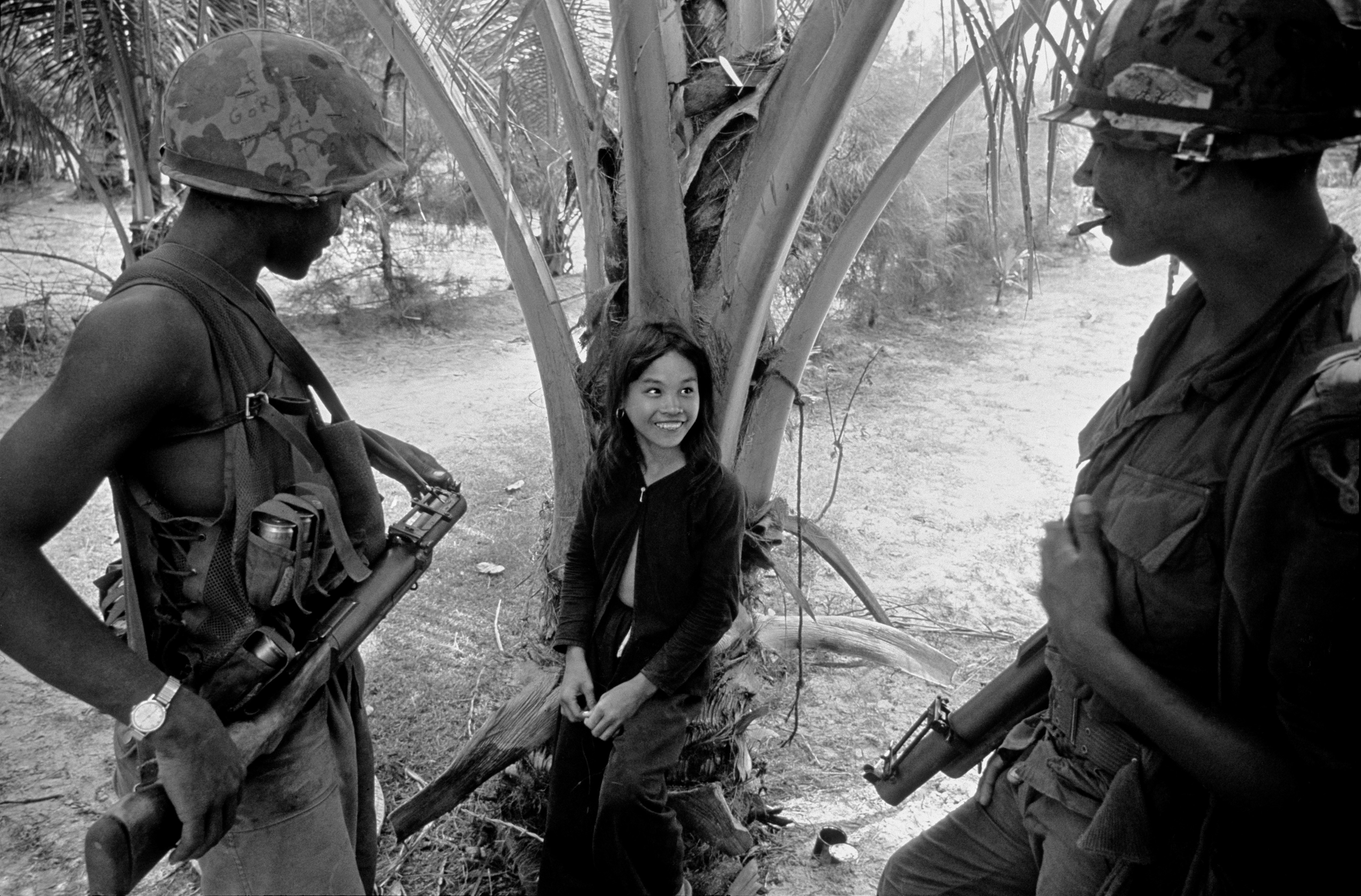 Two soldiers talking to a young girl in a South Vietnamese village.